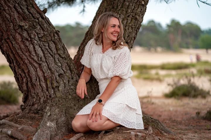 Jonge vrouw zittend bij boom tijdens datingshoot voor bumble in loonse en drunense duinen